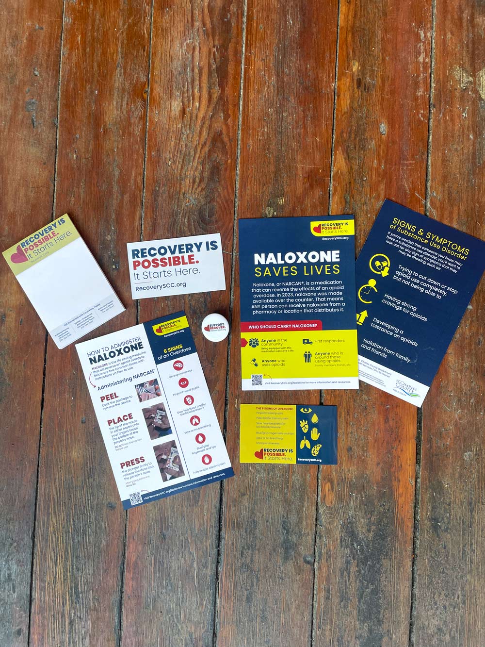 Several Naloxone graphics laid out on a wooden floor