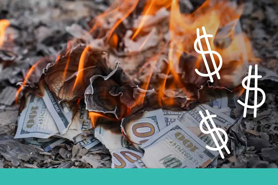 A pile of one-hundred-dollar bills burning in a fire with three white hand-drawn dollar signs floating above the flames. The image has a teal banner at the bottom.